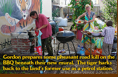 Gordon prepares some pheasant road kill on the BBQ beneath their new mural.  The tiger harks back to the land’s former use as a petrol station.